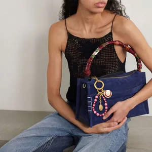 Blue suede handbag with printed silk-wrapped handle and tennis-themed charm pendant