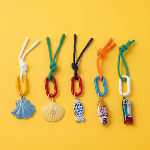 Five-piece set of nautical pendants with shell and fish charms on yellow background