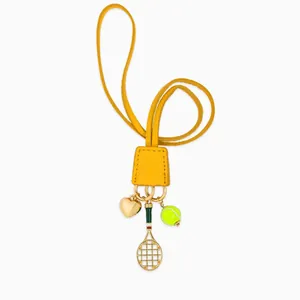 Détail d'un bijou de sac avec balle de tennis, raquette dorée et pendentif cœur
