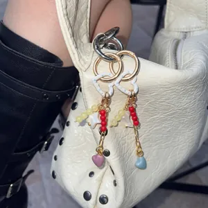 DIY colorful heart-shaped beaded keychain charms on a white textured luxury handbag