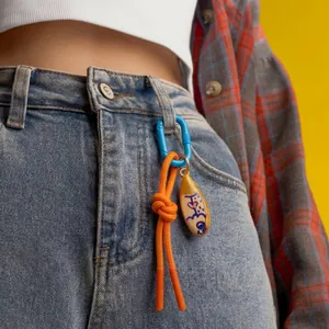 Colorful handmade bag charm with blue carabiner and orange rope on denim jeans