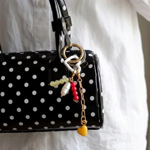 DIY minimalist gold keychain with freshwater pearl and heart pendant on a polka dot bag