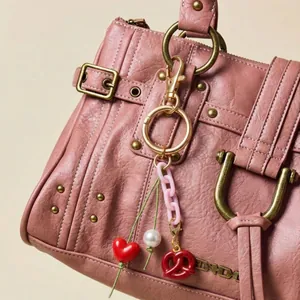 Porte-clés rose avec breloques cœur, perle et bretzel sur un sac en cuir rose
