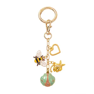Détail d'un porte-clés doré à thème insectes avec abeilles émaillées et breloques cœur