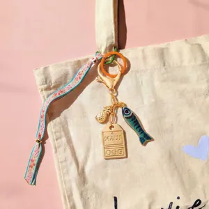 Tropische sleutelhanger met ananas, bloemenlint en Maui-label aan beige canvas tas