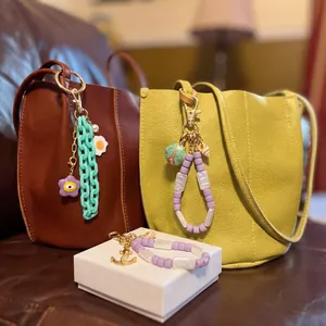 Colorful beaded bag charms with flowers and shells hanging on leather handbags