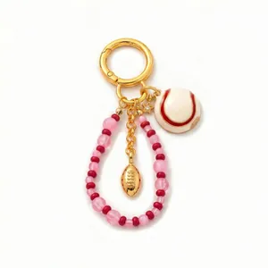 Detail of 18K gold plated sports keychain with baseball, rugby charms and beads