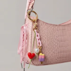 Bijou de sac rose avec cœur rouge, perle géante et pendentif glace sur fermoir mousqueton doré