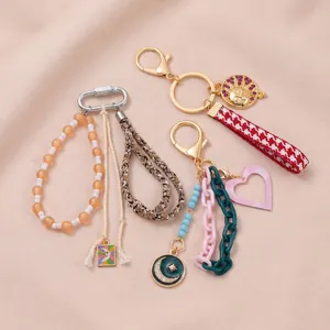 Three stylish DIY keychains with colorful beads and charms on pink textured fabric