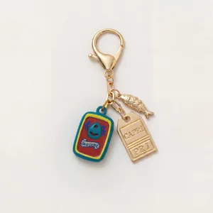 Detail van een sleutelhanger met sardineblikje, gouden vis en een Capri metalen label
