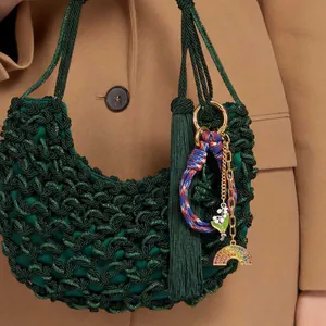 Deep green woven satin handbag with tassel and bell orchid charms on camel wool coat