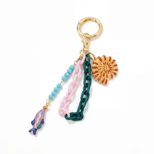 Detail van een DIY-sleutelhanger met kleurrijke acrylschakels en een schelphanger