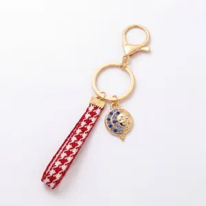 Detail of gold keychain with houndstooth strap and celestial sun moon charm