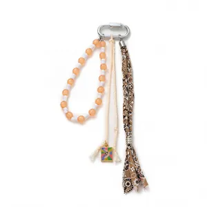 Bohemian keychain with beaded ring, cream tassel, and ethnic woven fabric on white background