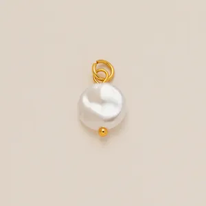 Dettaglio di un elegante ciondolo in perla bianca con doppio anello e piccola sfera dorata