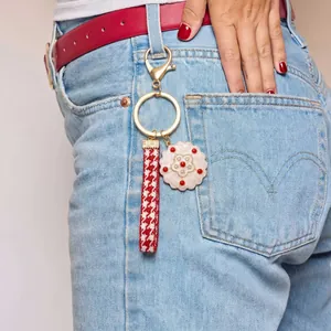 Fashionable strawberry keychain with houndstooth strap on blue denim jeans loop