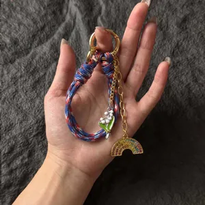 Handmade woven rope keychain with gold rainbow charm and lily of the valley floral pendant