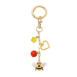 Porte-clés abeille doré chic avec perle rouge, fleur jaune et pendentif coeur évidé