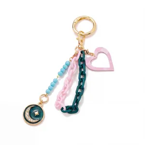 Detail of keychain with light blue beads, star-moon enamel charm and pink checkered heart