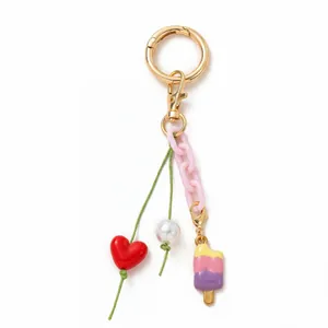 Détail d'un porte-clés DIY avec fermoir doré, chaîne rose et breloque glace colorée