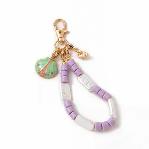 Detail of purple bead phone charm with shell pendant and gold lobster clasp