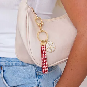 Fashion houndstooth strap keychain with floral pendant on a beige bag handle