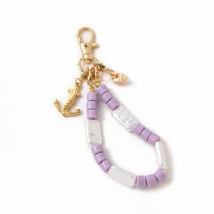 Close-up of ocean style beaded charm with golden anchor pendant and natural seashell