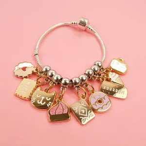 Macro detail of silver snake chain bracelet with golden dessert and cat charms