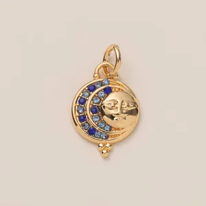 Detail of a celestial sun and moon charm with blue gems on a gold pendant