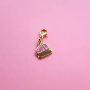 Detail of golden dessert pendant with pink glitter enamel and lobster clasp on pink background