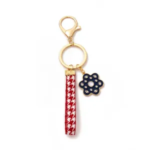Detailed close-up of fashion keychain with red houndstooth ribbon and blue flower charm