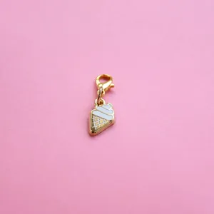 Macro detail of gold-plated ice cream pendant with white enamel and lobster clasp