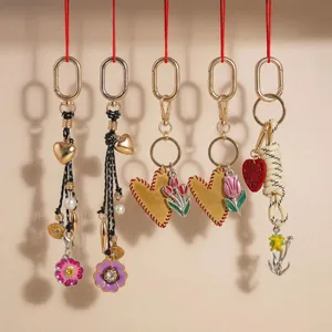 Five assorted creative bag charms featuring braided hearts, pearls, and floral tulip motifs