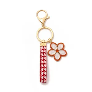 Detail of floral keychain with houndstooth ribbon and orange rhinestone flower charm