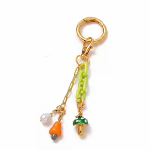 Detail van 18K gouden sleutelhanger met groene ketting, parel en paddenstoelhangers