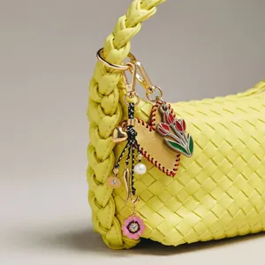 Close-up of yellow woven leather handbag featuring colorful heart and flower charms