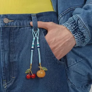 Close-up of handmade woven fruit bag charms with colorful beads on blue denim