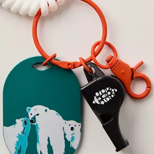 Macro view of fish-themed charm with orange ring, black whistle and polar bear tag