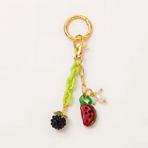 Detail view of 18K gold-plated keychain with watermelon and blackberry fruit charms