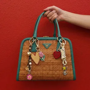 Handwoven straw tote with teal leather trim and colorful heart flower charms