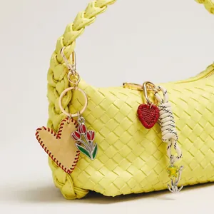 Yellow woven leather handbag with heart charms and floral metal pendants details