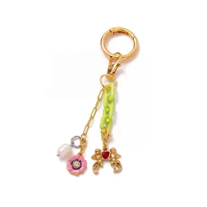 Detail of 18K gold keychain with green acrylic chain and red heart angel pendant