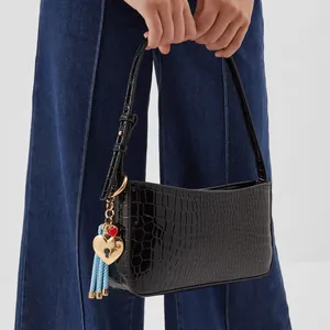 Detail of black crocodile texture bag with heart lock and blue striped tassel charm