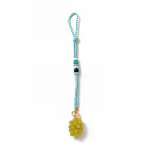 Detailed macro of handmade woven lanyard with colorful beads and green grape charm