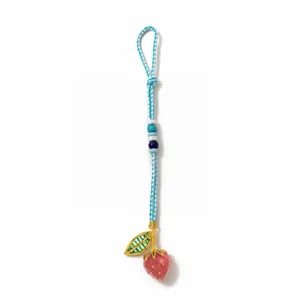 Detail of a handmade pink strawberry bag charm with woven cord and colorful beads
