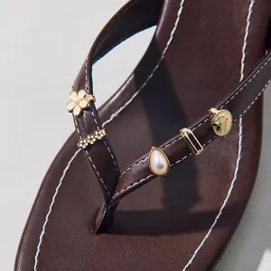 Brown leather flip flops with blue floral charms and pearl accents for summer style