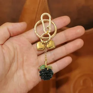 Golden keychain featuring heart charms and a black berry pendant with green crystals