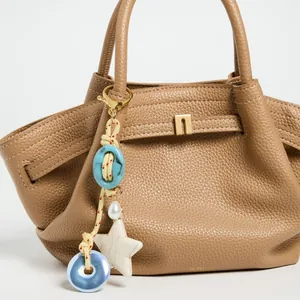 Detail of colorful ceramic beaded bag charm with star and heart pendant on leather bag