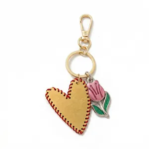Detail of yellow leather heart with red stitching and pink tulip keychain charm