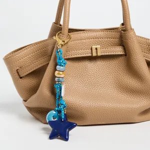 Detail of blue ceramic bead charm with star pendant on a leather handbag strap